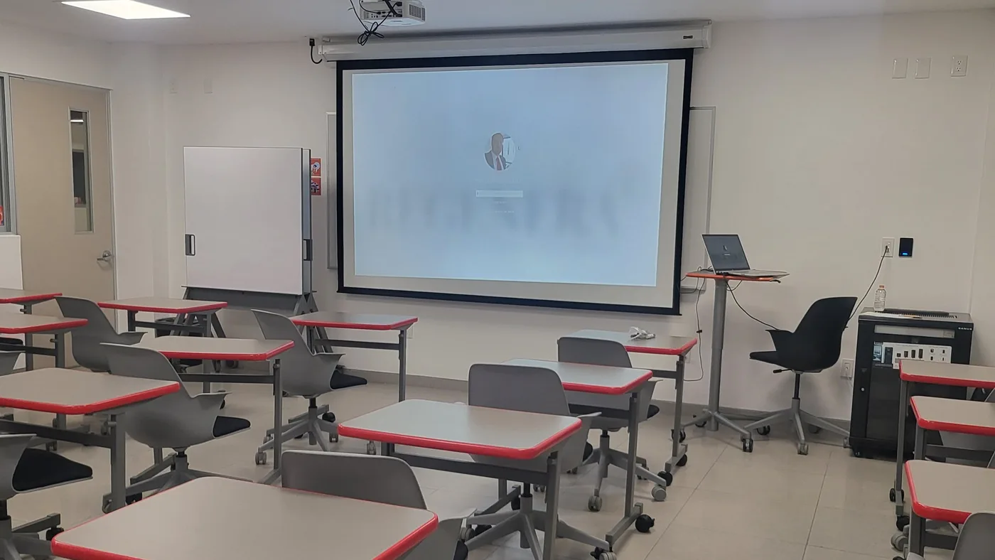 Salle de classe avec pupitres, écran de projection et pupitre d’orateur, prête pour un cours